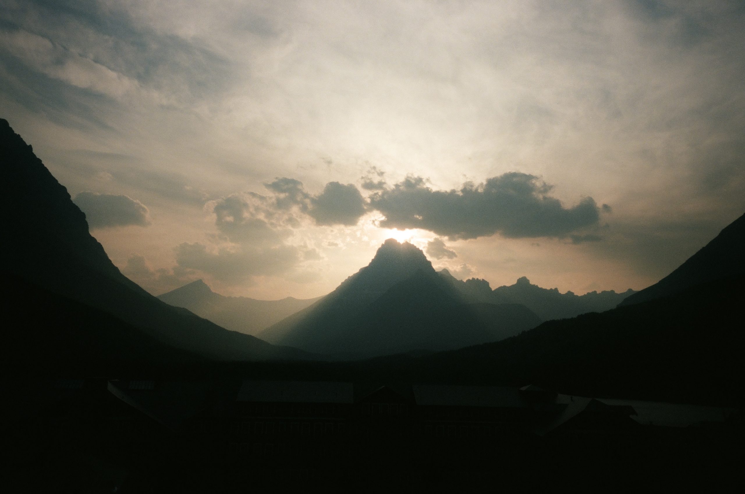 Sun setting behind mountain with clouds