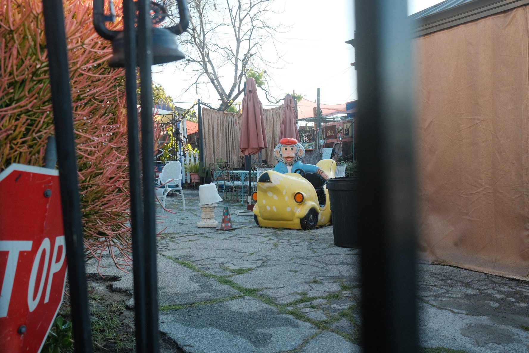 A photo taken between gate bars of a monkey riding a banana ride