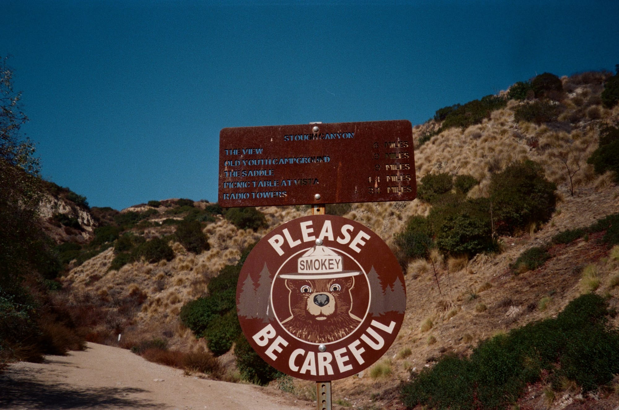 Photo of a trail sign with Smokey the bear that says “Please Be Careful”